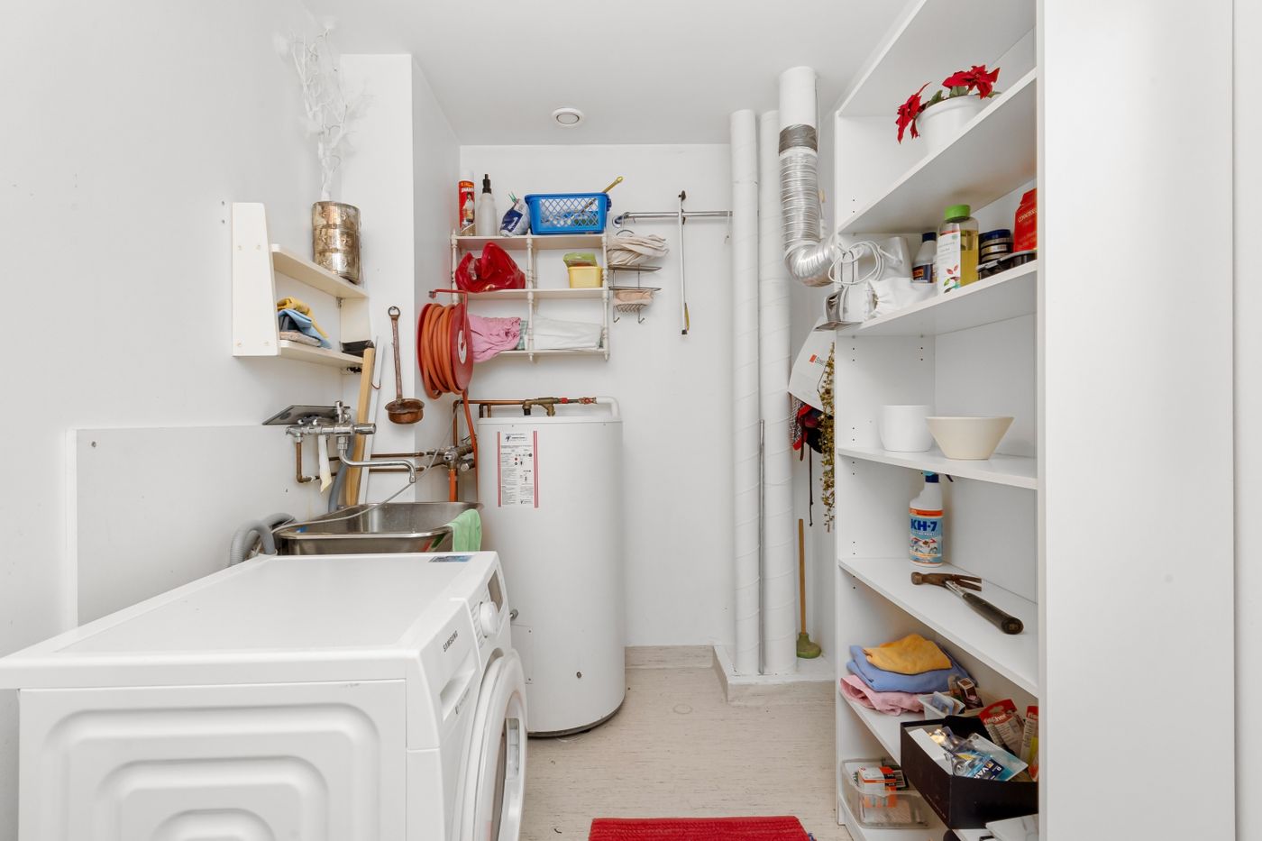 A storage tank water heater standing in a home utility room beside a washing machine